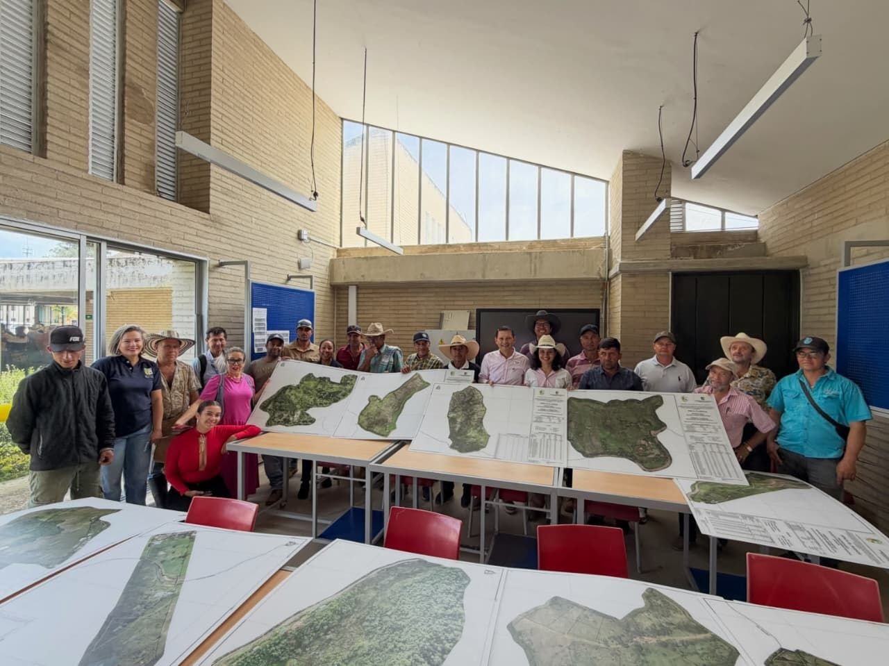 La entrega de los planos impresos: los propietarios de un corregimiento posan con el mapa de su predio sobre las mesas.